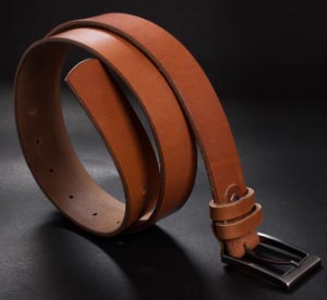 Cintur&oacute;n masculino de piel enrollado con hebilla sobre el suelo - Categor&iacute;a de cinturones masculinos.
